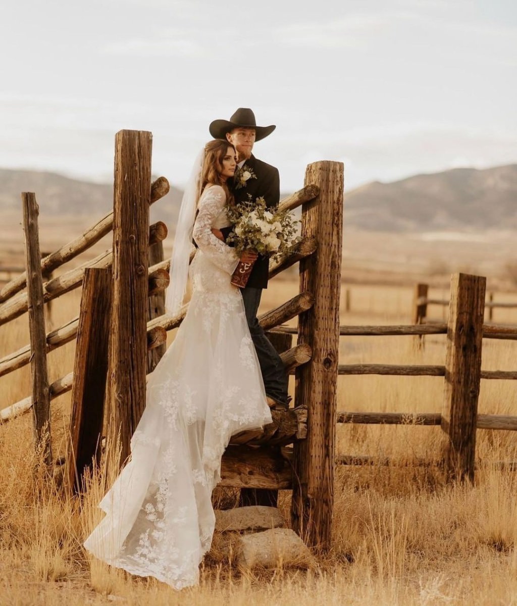 A gorgeous wedding photo that shows a bride and room on a ranch posing for their rustic-style photos