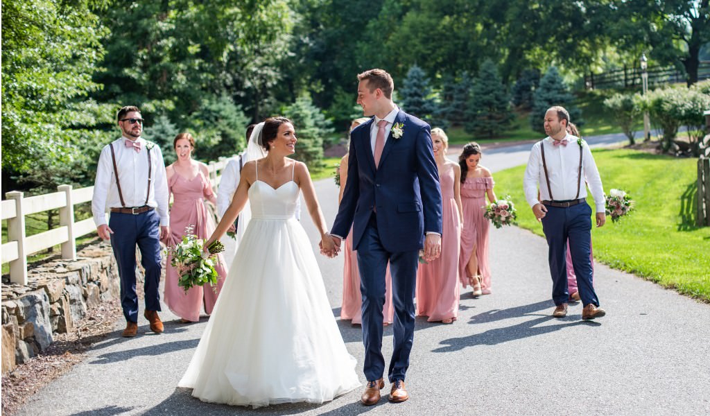 A wedding party having a great time together as they take a walk down the road