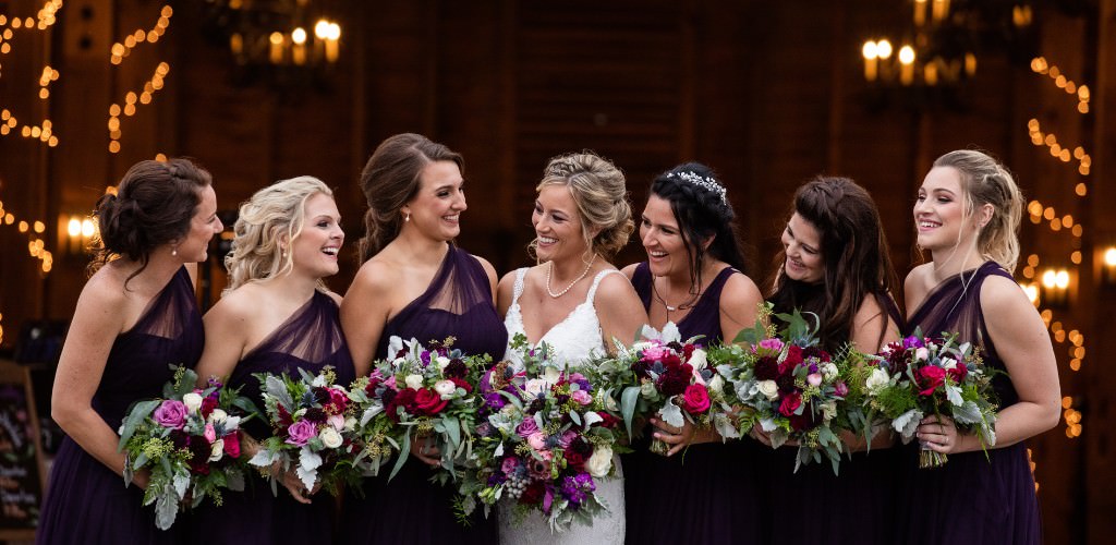 A bride and bridesmaids looking at each other and smiling