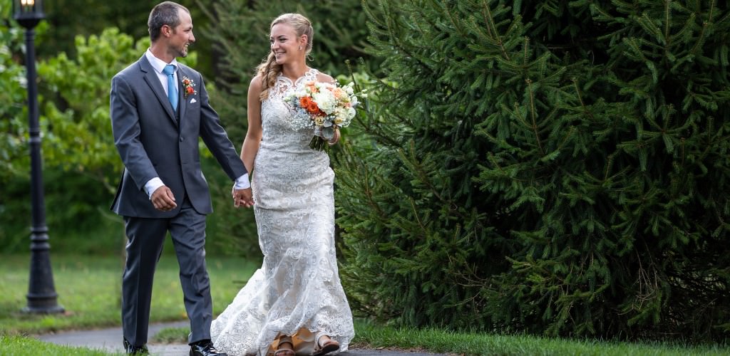 A bride and groom walking in the trees