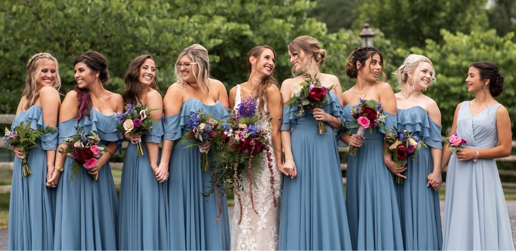 A bride and bridesmaids posing. The bridesmaids are wearing blue rented bridesmaid dresses.