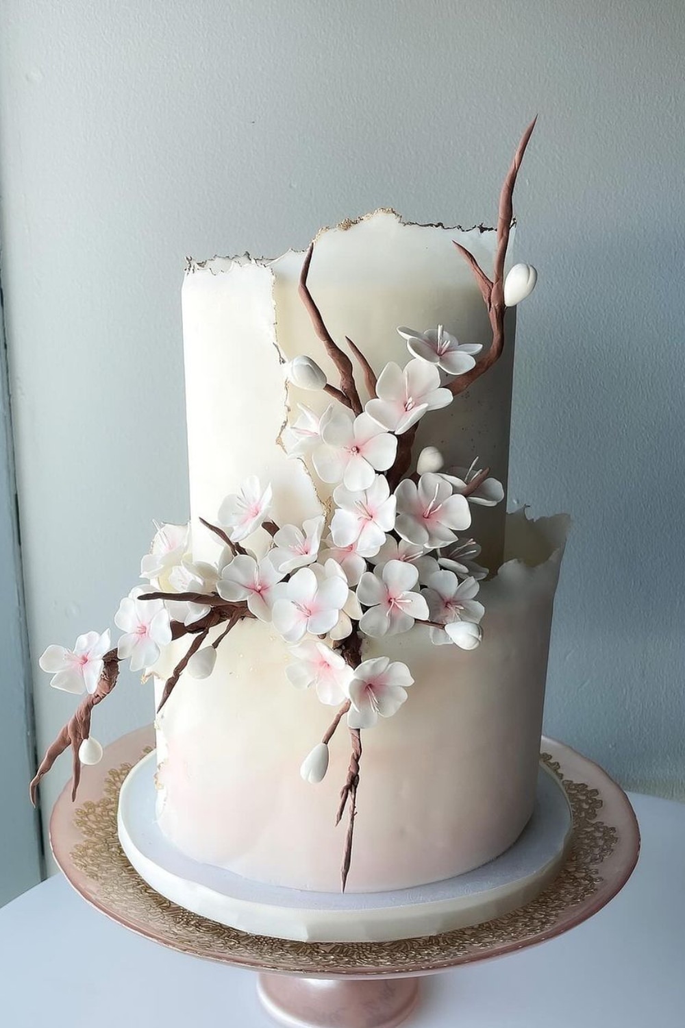 A modern two tier wedding cake with flowers and branches