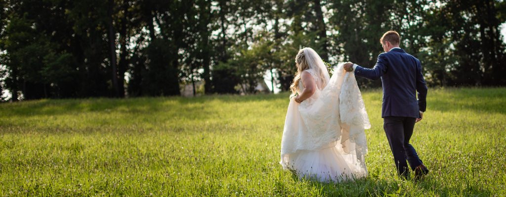 A bride and groom walking in a field on the wedding day