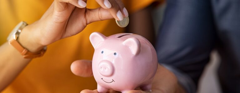 A couple putting money into a piggy bank