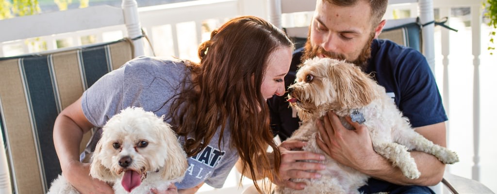 A couple sitting in rocking chairs outside with their two little dogs. These were taken for their engagement photos