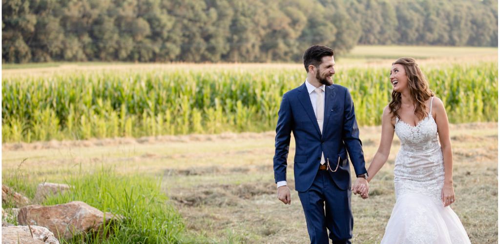 A bride and groom walking in a field. This is for the blog post called helpful wedding planning tips from real brides