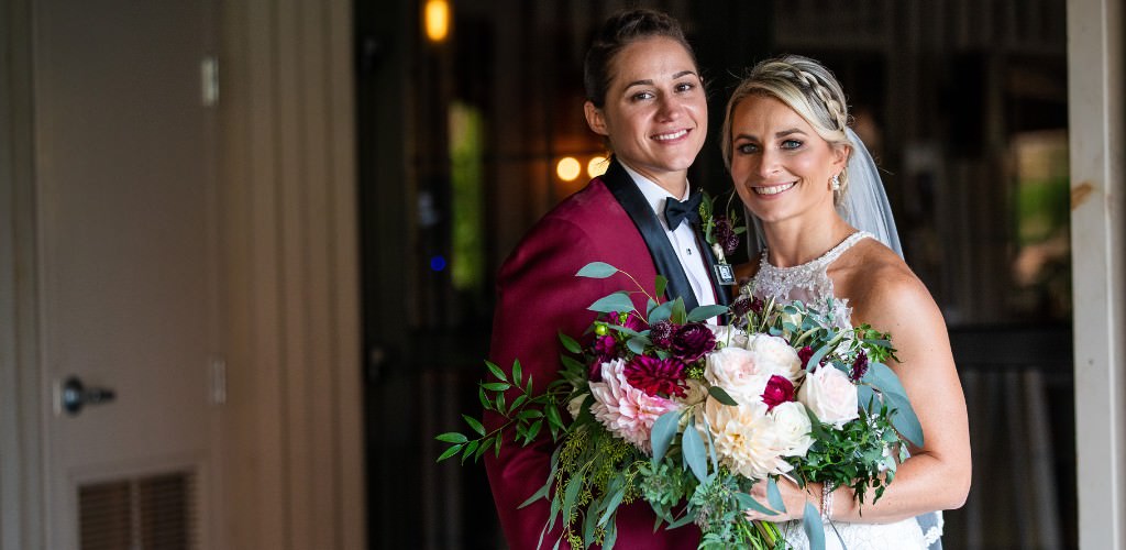 Two brides posing for the camera on their wedding day