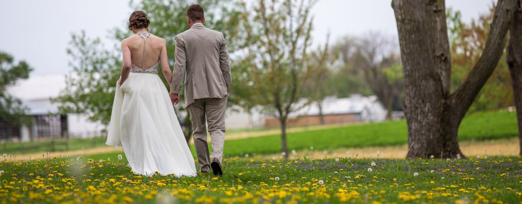 A bride and groom walking through a field of yellow flowers after the wedding ceremony