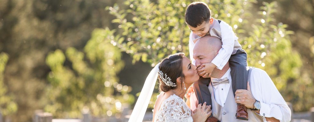 A bride and groom posing with their kid on the wedding day