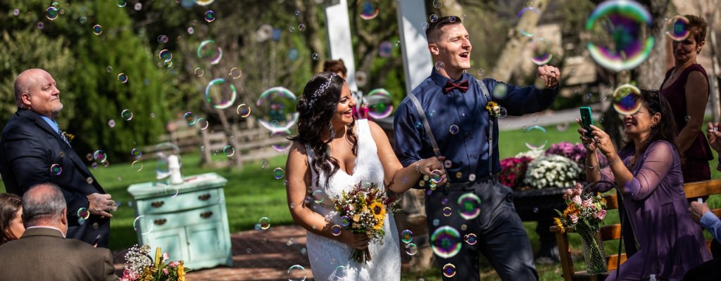 A bride and groom walking through bubbles as they exit the wedding ceremony