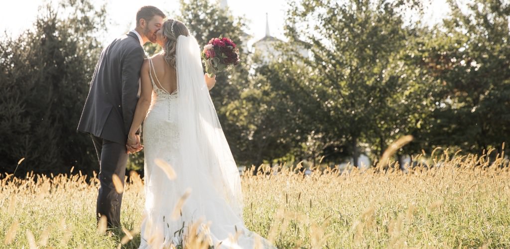 A bride and groom kissing in a field