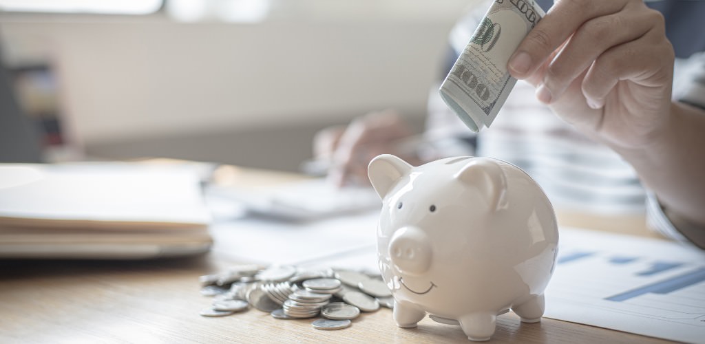 A groom putting a $100 bill into a small piggybank