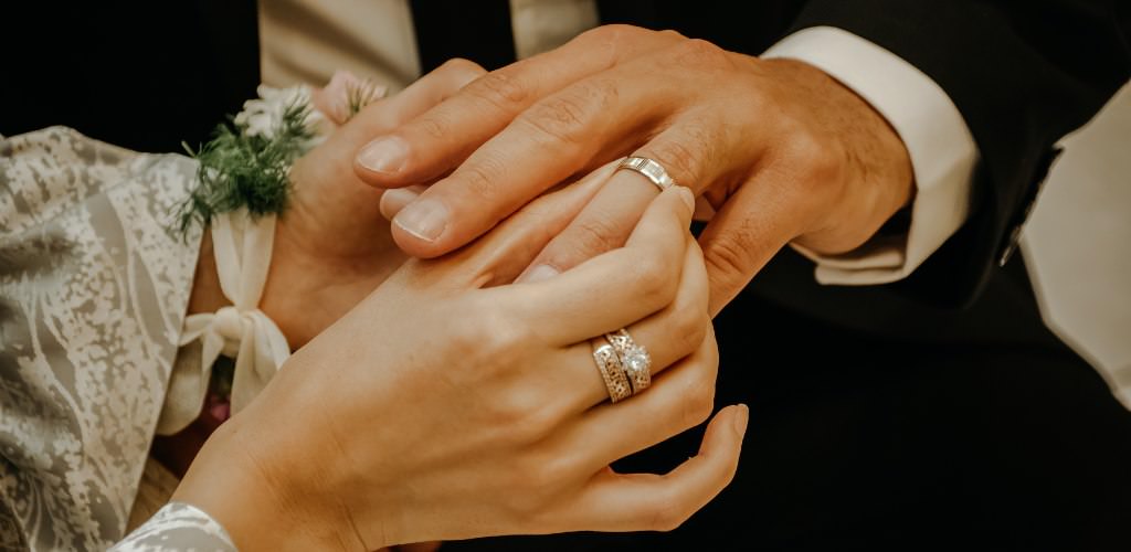 A bride putting a wedding ring on a groom's hand