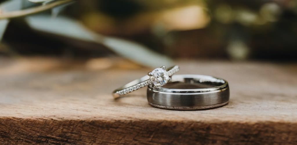 Two wedding rings sitting on a wooden surface.