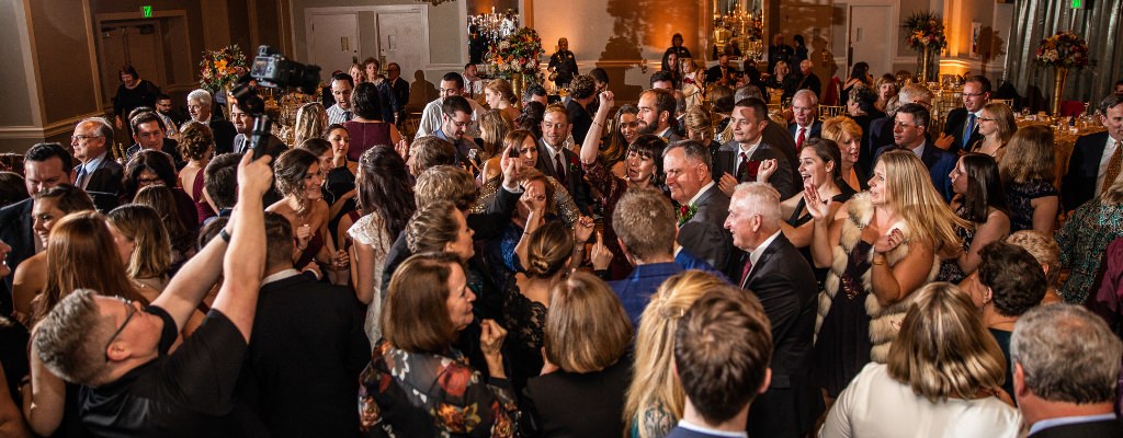 A packed dance floor at a wedding reception. This is the first photo for the blog post called must play wedding reception songs