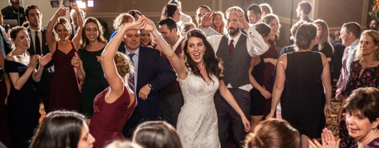 A bride dancing in the middle of the dance floor at a wedding reception and all of the guests are around her