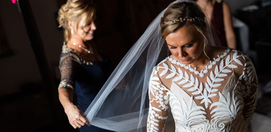 A bride's mom putting on the bride's bridal veil