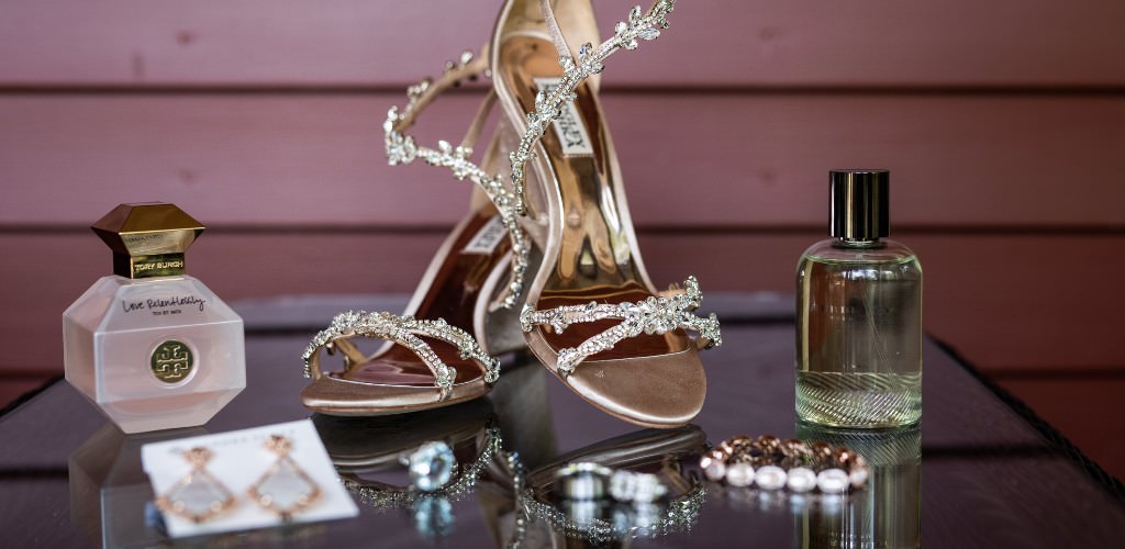 A collection of bridal details like shoes, jewelry, and perfume