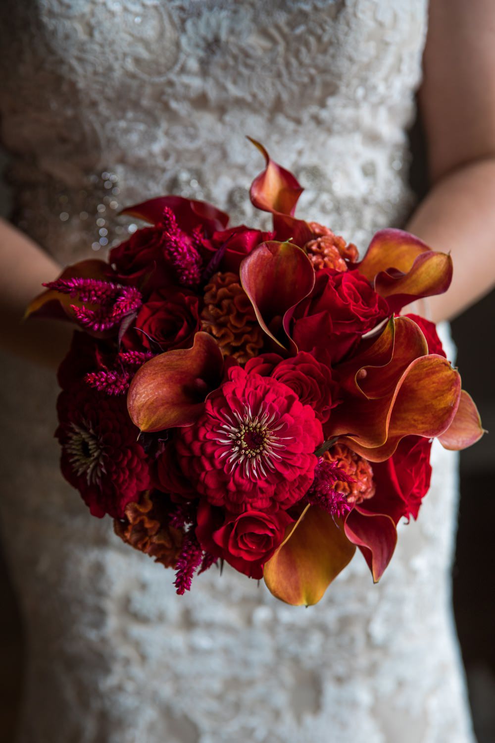 A tight round red and orange bridal bouquet for a wedding