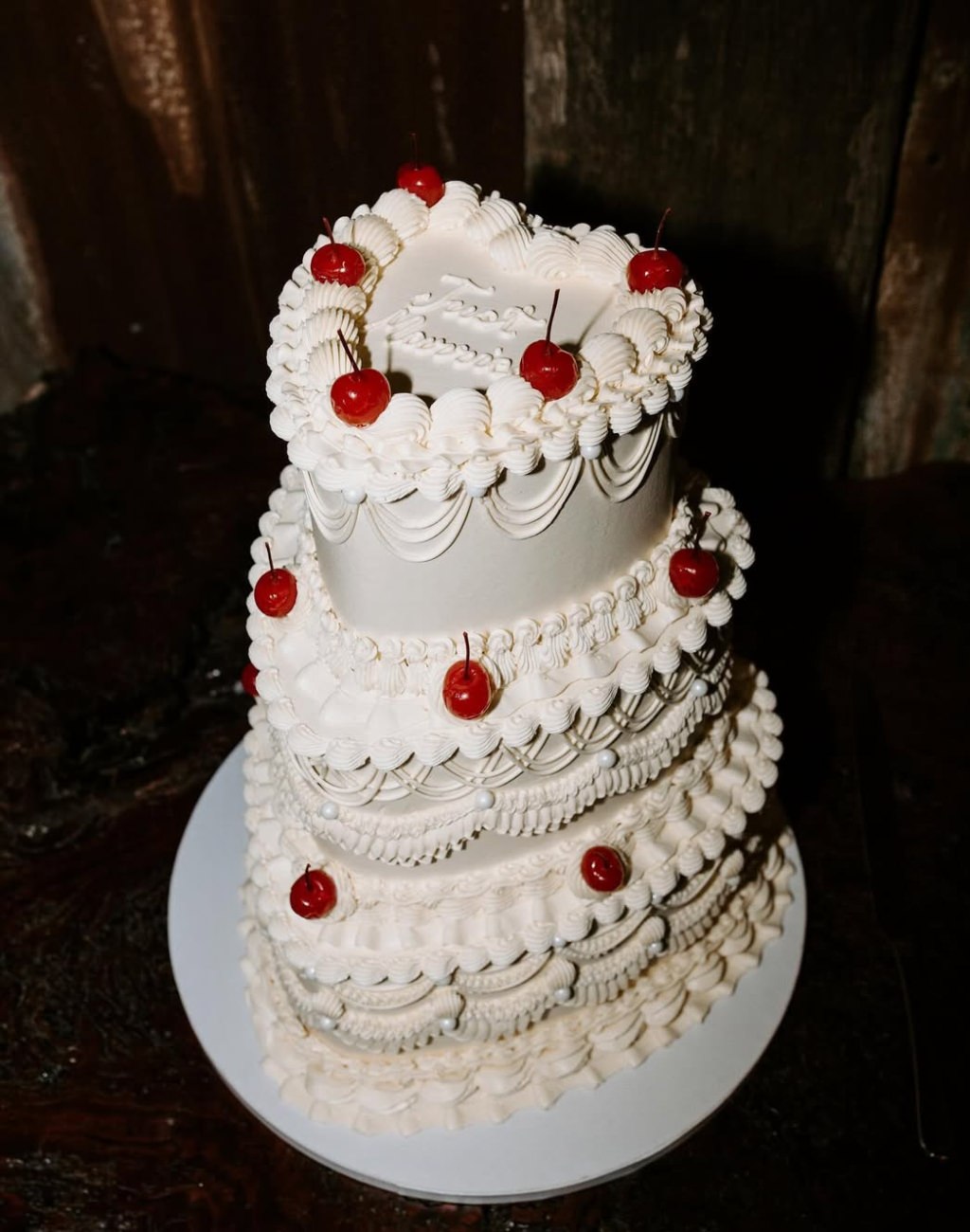 A modern 3-tier heart shaped wedding cake with red cherries