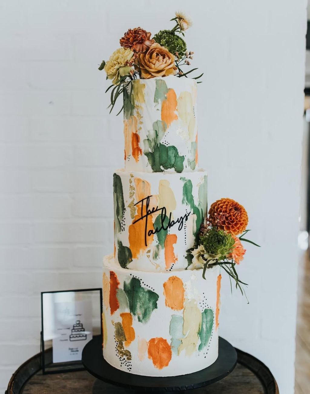 A stunning 3-tier wedding cake with orange and green decor