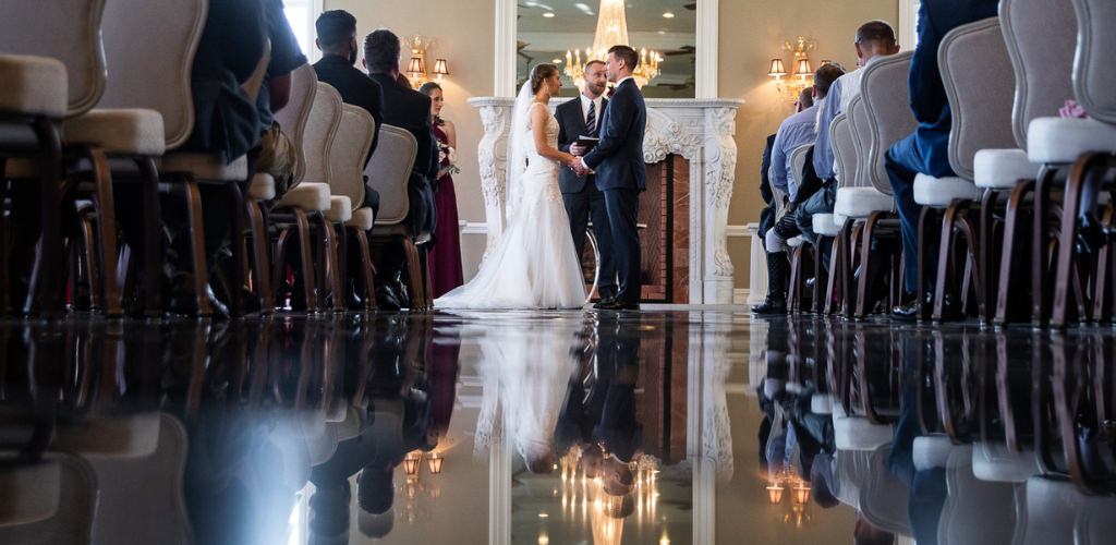 A bride and groom getting married and their reflection is showing on mirror floor