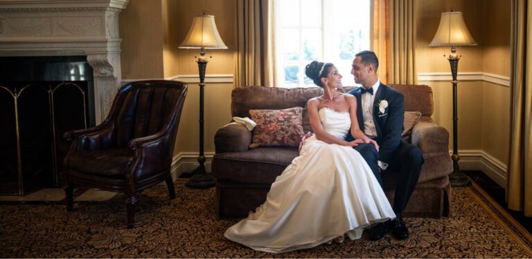 A bride and groom sitting on a couch smiling at each other. This is for the blog post called 6 month wedding planning timeline