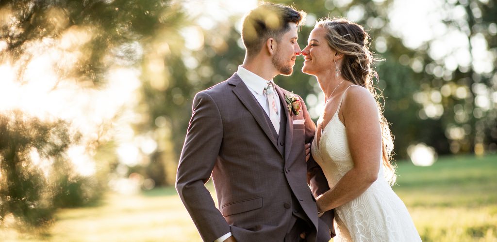 A bride and groom looking at each other and smiling in the woods