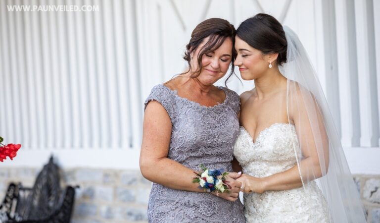 A bride and her mom sharing a quiet moment together on the wedding day. They are touching foreheads and smiling with their eyes closed