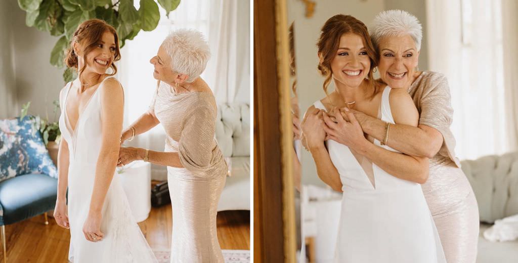 A mom helping the bride get dressed and smiling at each other