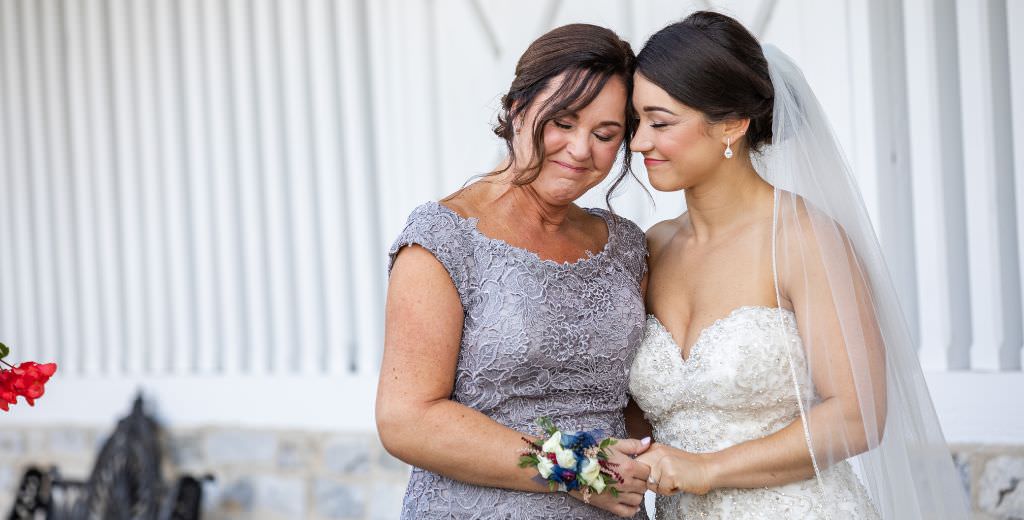 A bride and her mom sharing a quiet moment together with their eyes closed. This is for the blog post called mother of the bride responsibilities