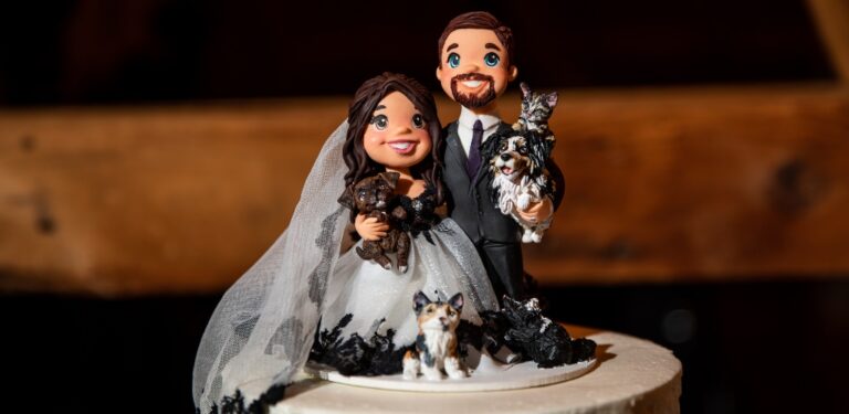 A custom made wedding cake topper showing the couple, their two dogs, two cats, and their pet skunk