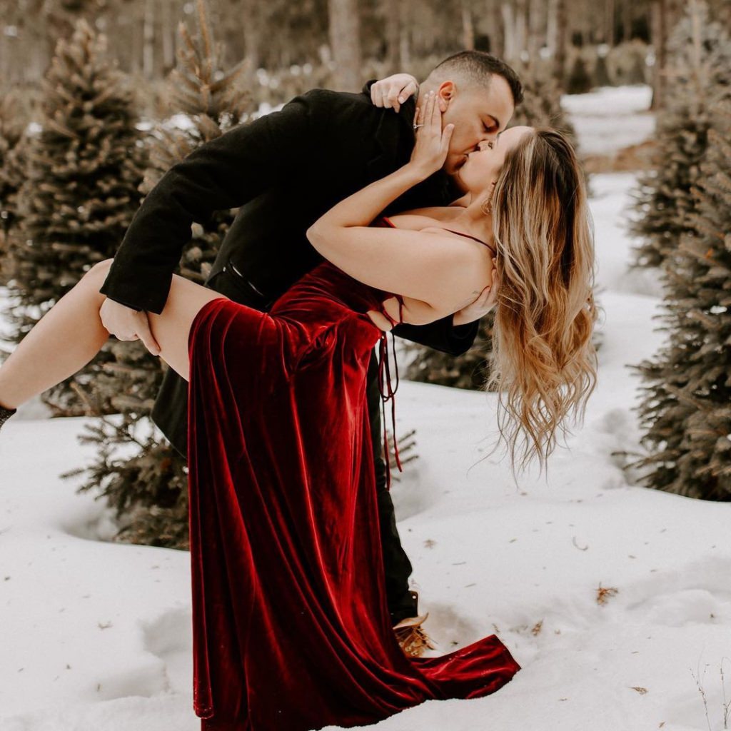 A man dipping a girl in a red dress in the snow