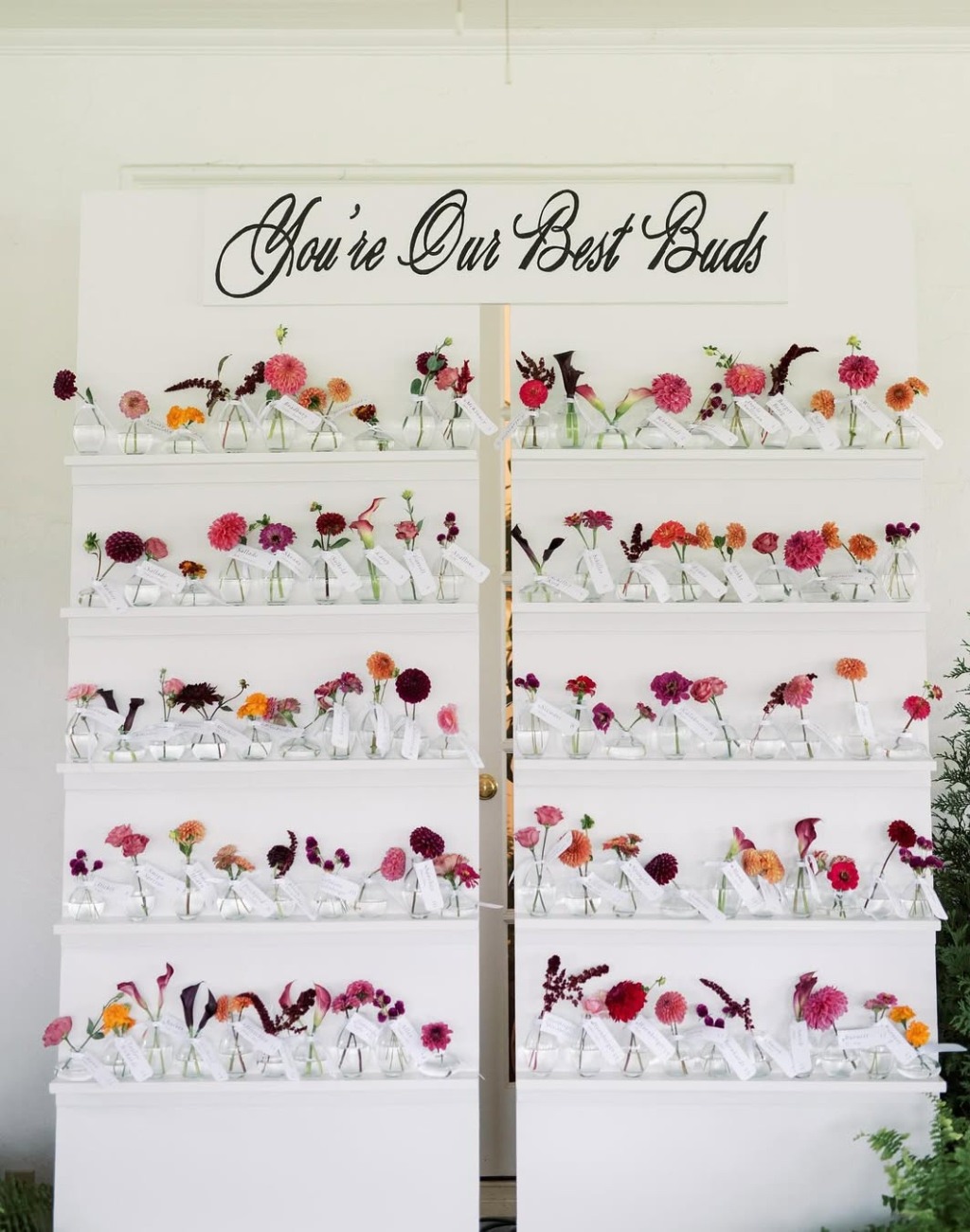 A cute wedding seating chart idea that has little vases with flowers for each guest and table number