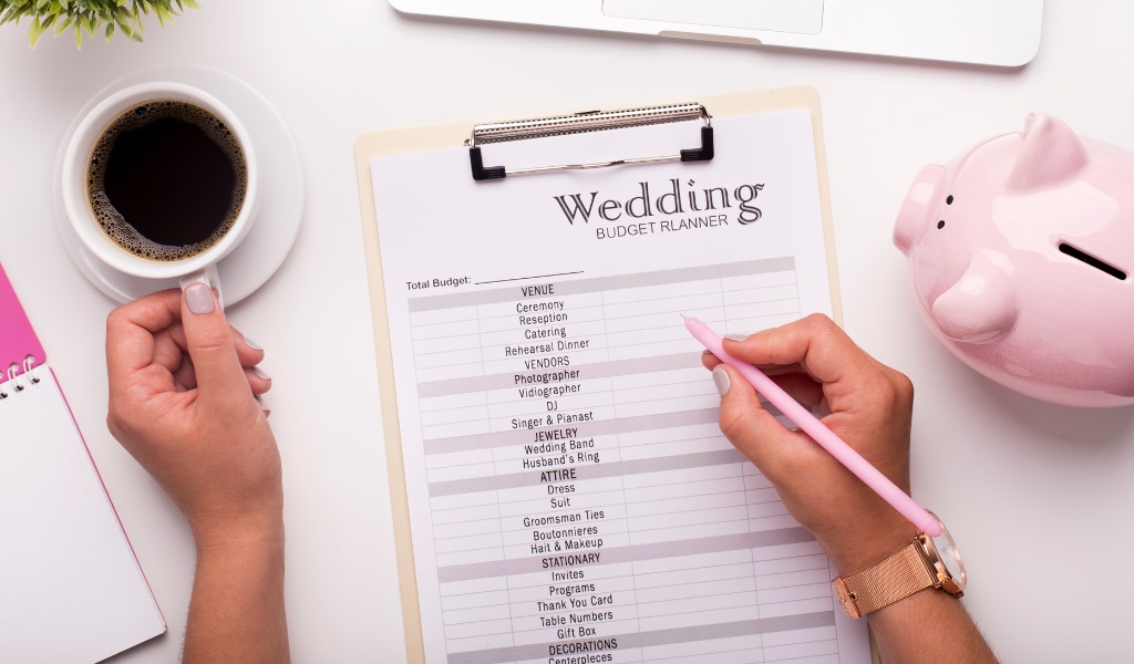 A close up of a woman filling out a wedding budget tracker
