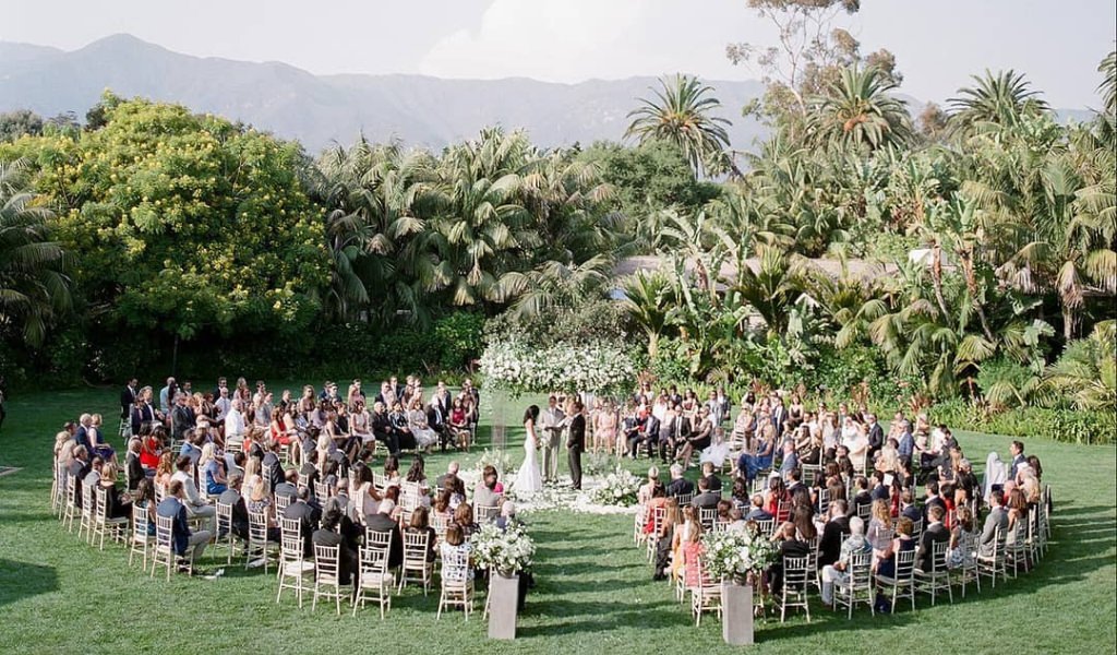 A wedding ceremony with circular seating where the guests are surrounding the couple