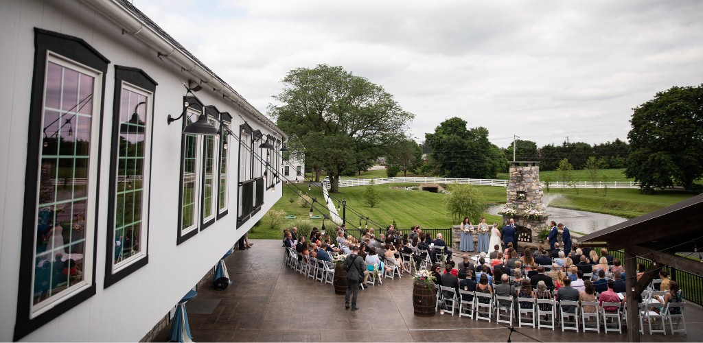 An outdoor wedding ceremony happening right next to the wedding reception venue