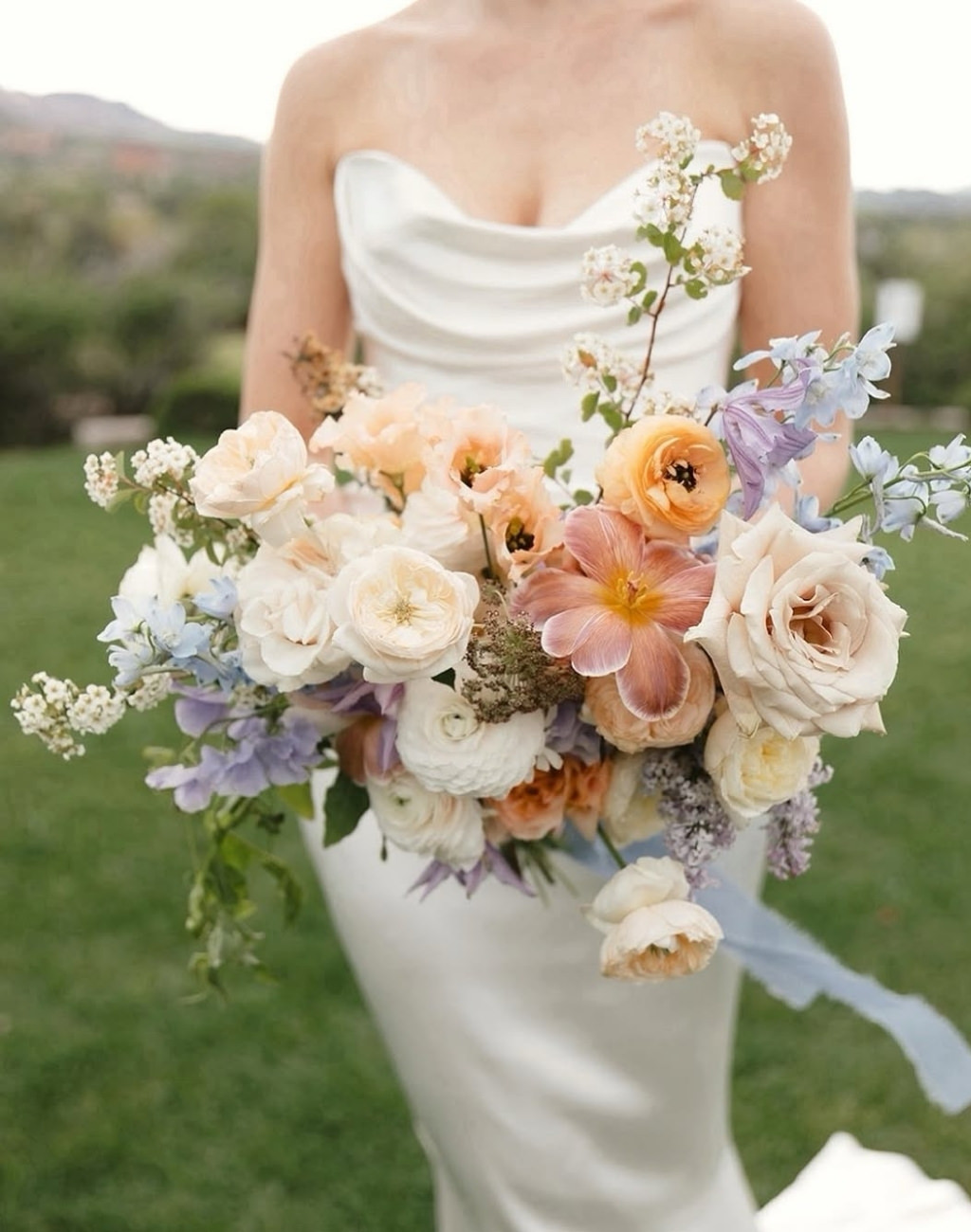 A soft pretty spring wedding bouquet with lavender, blush, and peach flowers