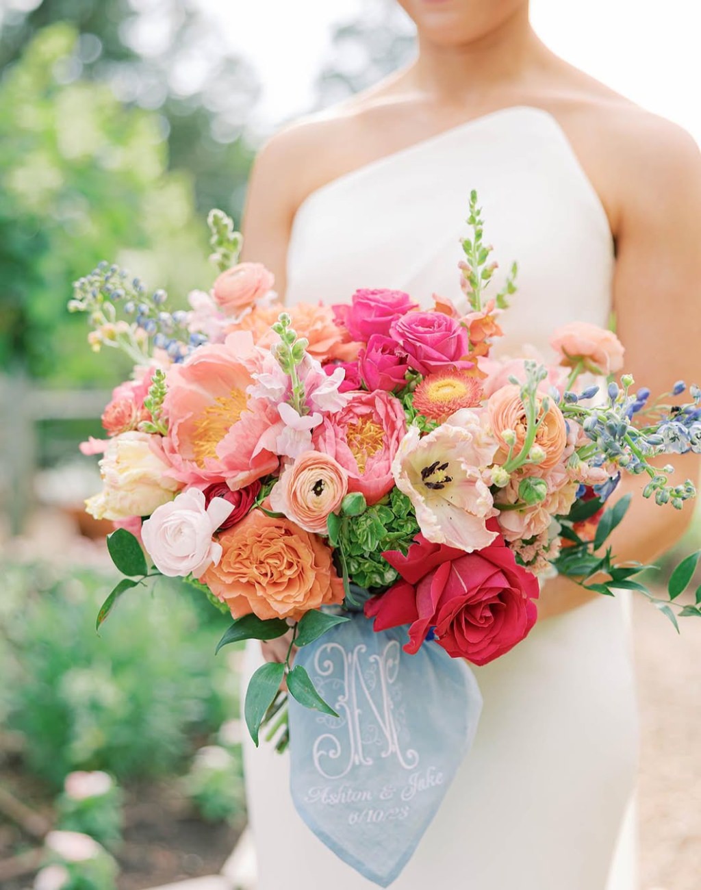 A spring wedding bouquet with pink, peach, red, and blush flowers