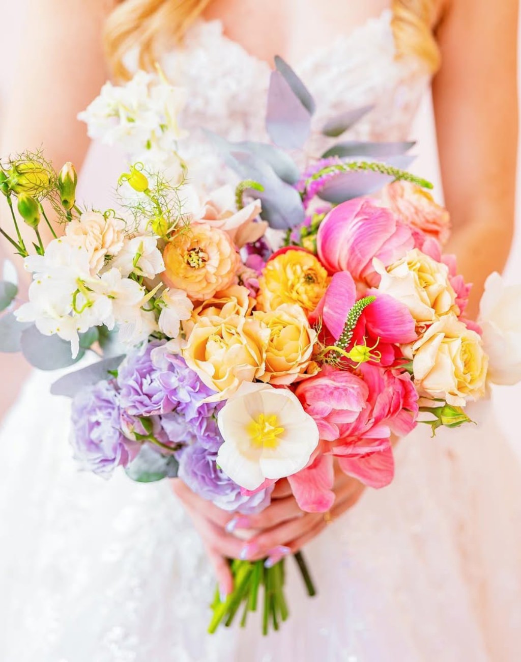 A spring wedding bouquet with a rainbow full of colors like purple, lavender, yellow, and pink