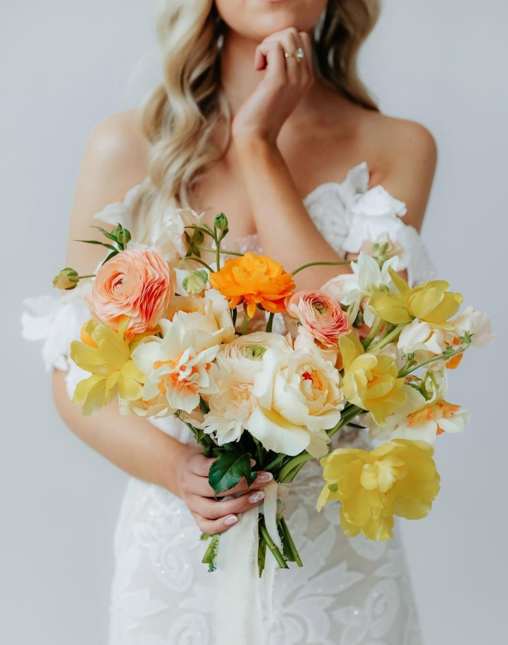 A spring wedding bouquet with yellow, orange, and peach colored flowers