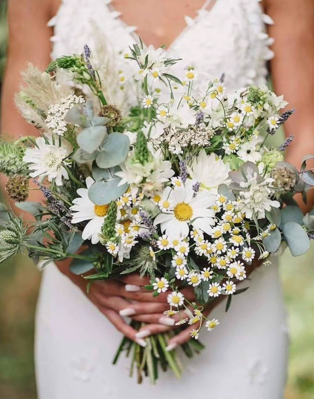 A stunning summer wedding bouquet with white and yellow daisies and other pretty flowers