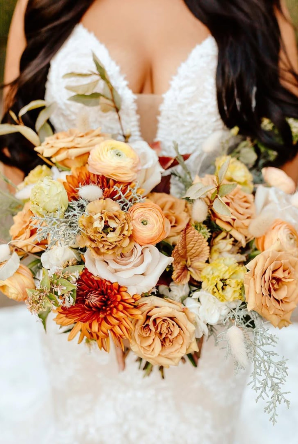 A big fall wedding bouquet with orange colored flowers